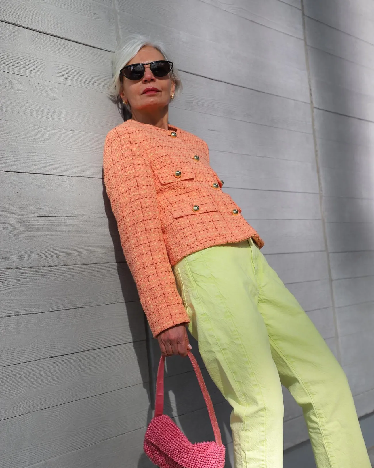 peach fuzz boucle jacket paired with lime green pants and a ontreasting pink bag