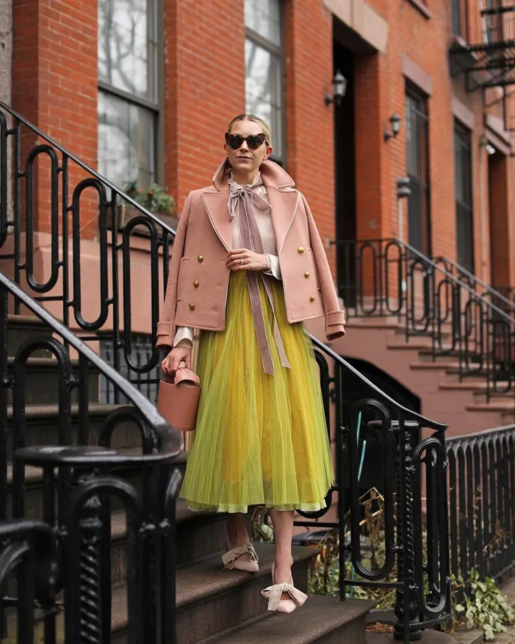 short peach fuzz trench coat paired with a contrasting neon yellow tulle skirt